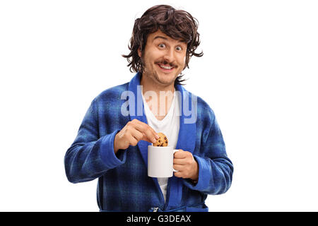 Homme tenant une tasse de lait et de trempage d'un biscuit aux brisures de chocolat dans il isolé sur fond blanc Banque D'Images