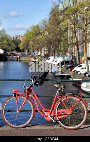 Vélo rouge sur un pont sur le canal Herengracht dans le centre-ville d'Amsterdam, Pays-Bas. Banque D'Images