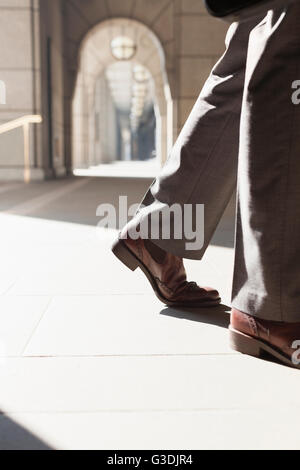 Pieds de corporate businessman walking in sunny cloître Banque D'Images