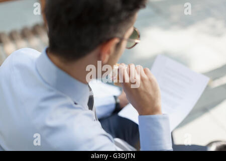 Corporate businessman eating le déjeuner et les documents de lecture Banque D'Images