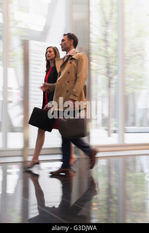 Corporate businessman and businesswoman walking and talking in corridor Banque D'Images