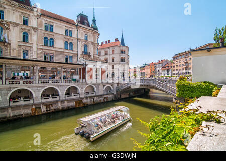 Ljubljana, Slovénie - 7 juin 2016 Bateau sur la rivière Ljubljanica et triple des ponts dans l'arrière-plan sur une journée ensoleillée Banque D'Images