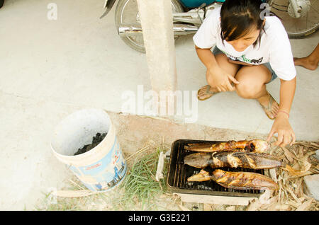 Les femmes thai cooking clarias est une espèce de poisson-chat marche thai style frites grillées sur vieille cuisinière Banque D'Images