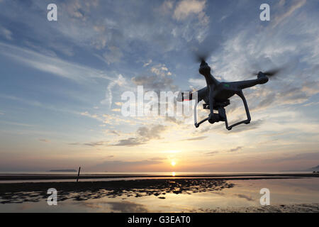 Drone voler contre un ciel de coucher du soleil Banque D'Images