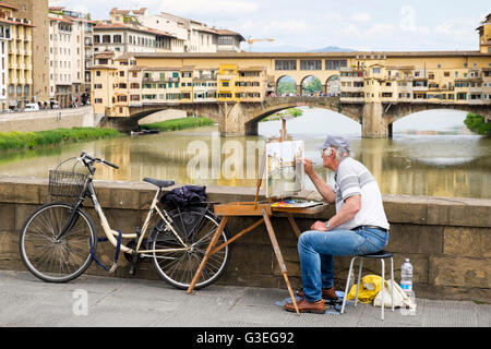 Un artiste sur le Ponte Santa Trinita à Florence, Italie, travaillant sur une peinture du Ponte Vecchio vu dans l'arrière-plan. Banque D'Images