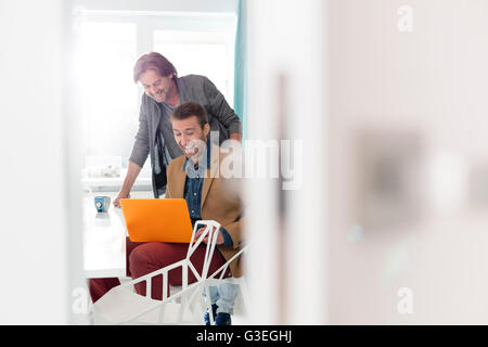 Hommes d'enthousiaste using laptop in office Banque D'Images
