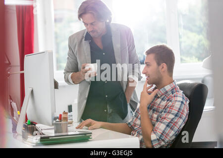 Boire du café et des hommes d'affaires travaillant à computer in office Banque D'Images