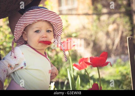 Funny baby girl au Panama hat walking in park parmi les fleurs en fleurs à sunny summer day with copy space Banque D'Images