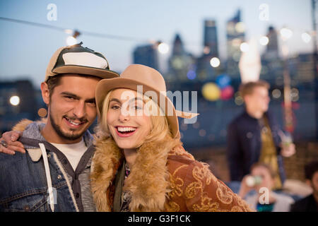 Portrait of smiling young couple hugging at rooftop party la nuit Banque D'Images