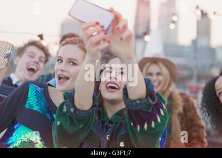 Les jeunes femmes de rire et de prendre parti sur le toit à selfies Banque D'Images