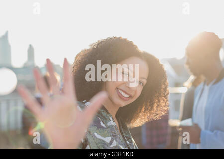 Portrait smiling woman waving at rooftop party Banque D'Images