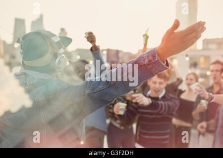 Young adult friends cheering pour DJ at rooftop party Banque D'Images