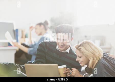 Jeune couple drinking coffee and using laptop Banque D'Images