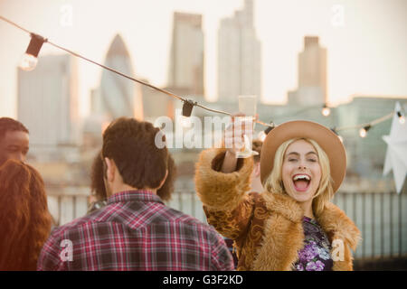 Portrait jeune femme enthousiaste drinking champagne at rooftop party Banque D'Images