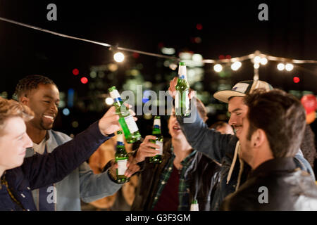 Jeunes gens qui buvaient de la bière et la danse at rooftop party Banque D'Images