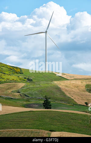 Seule éolienne fournissant de l'énergie renouvelable au sommet d'une colline rural agricole avec des champs et des prés en dessous contre un nuage Banque D'Images