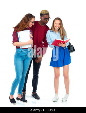 Trois heureux jeune adolescent students standing et souriant avec des livres, ordinateur portable et sacs isolé sur fond blanc Banque D'Images