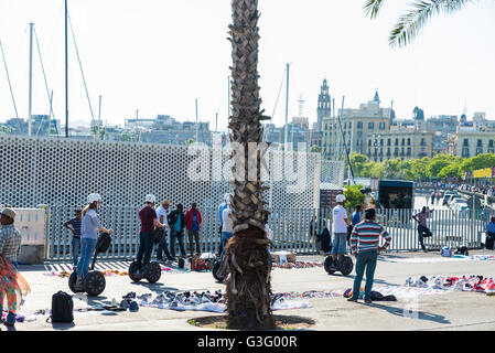 Les touristes sur un segway dans la promenade du front de mer plein de touristes et avec un marché aux puces à Barcelone, Catalogne, Espagne Banque D'Images