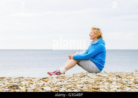 Femme assise sur la plage et regarde dans la distance Banque D'Images