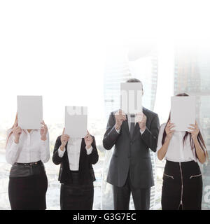 Portrait des gens d'affaires groupe holding white papers et couvrant leurs visages Banque D'Images