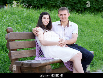 Femme enceinte et mari sur l'extérieur, une famille heureuse, en couple dans la région de city park, saison d'été, l'herbe verte et des arbres Banque D'Images