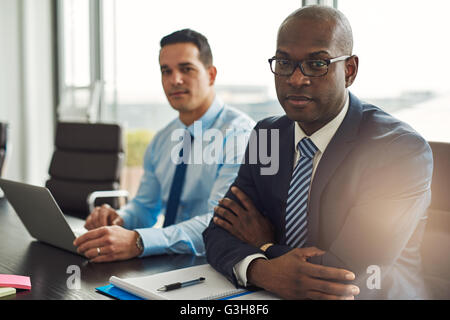 Les partenaires d'affaires multiraciale dans une réunion avec un jeune homme d'origine hispanique à l'aide d'un ordinateur portable et d'African American man Banque D'Images