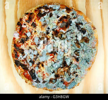 Vieux moldy pizza sur une table en bois. L'intoxication alimentaire Banque D'Images
