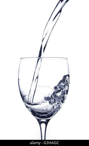 Verser de l'eau dans un verre sur un fond blanc Banque D'Images