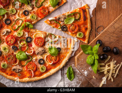 Pizza végétarienne fait maison sur une table en bois. Les ingrédients de la pizza sont des champignons, olives noires, fromage mozzarella Banque D'Images