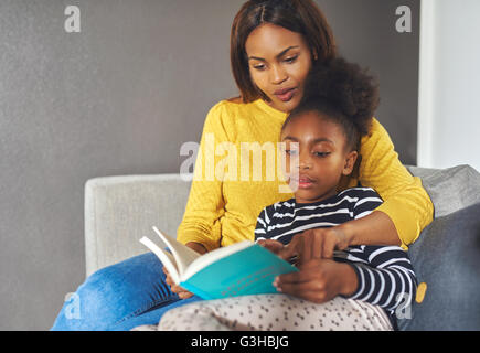 Mère et fille lire un livre à la lecture excité Banque D'Images