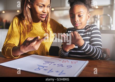 Heureux enfant qui apprend à calculer à la maison, mère noire et sa fille faire ses devoirs Banque D'Images