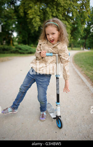 Petite fille d'être appuyée sur une roue du scooter. Il s'est arrêté pour prendre le reste. Banque D'Images