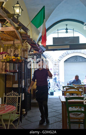 Serveur dans le restaurant Osteria Vecchio Via café du centre de Florence avec drapeau italien Banque D'Images