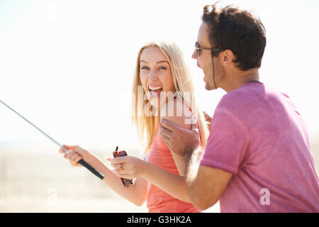 Couple de jouer en plein air, woman holding stick selfies, rire Banque D'Images