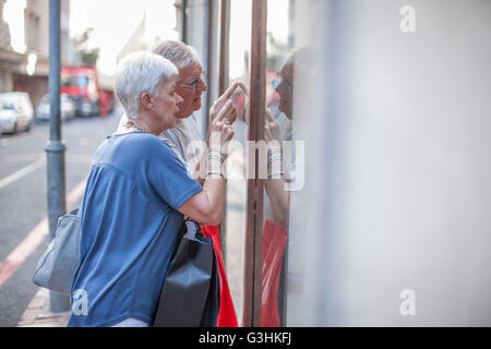 Senior couple pointing at city shop window Banque D'Images