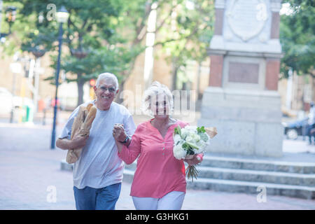 Portrait of happy senior couple carrying baguettes et bouquet à city Banque D'Images