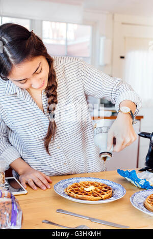 Femme en versant le sirop sur cuisine gaufre frais Banque D'Images