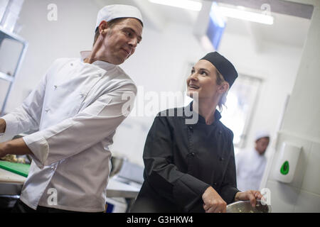 Chat et les chefs preparing food in kitchen Banque D'Images