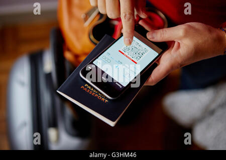 Woman holding passport et smartphone, smartphone montrant QR code, overhead view Banque D'Images