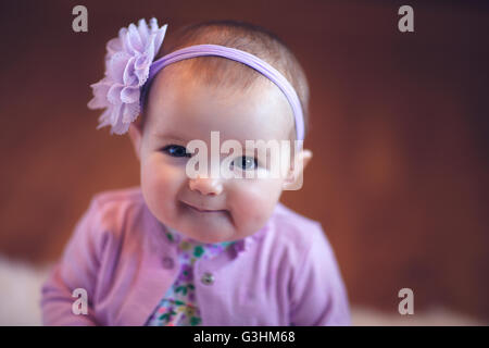 Portrait of baby girl wearing headband fleuri smiling at camera Banque D'Images