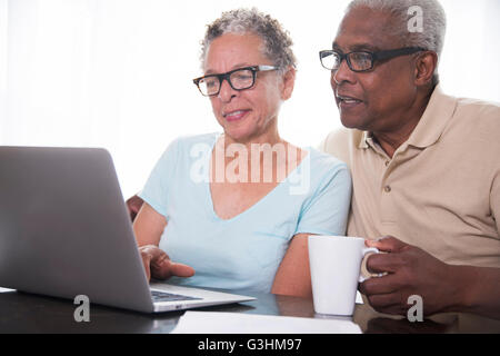 Senior couple sitting at table, using laptop Banque D'Images