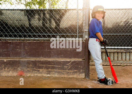 Portrait of boy leaning against clôture à l'entraînement de base-ball Banque D'Images