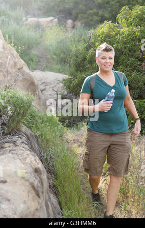 Femme hiker holding bouteille d'eau en plastique smiling Banque D'Images