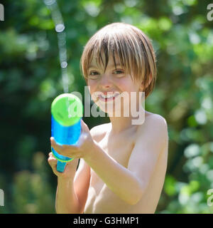 Portrait of boy squirting canon à eau au jardin Banque D'Images