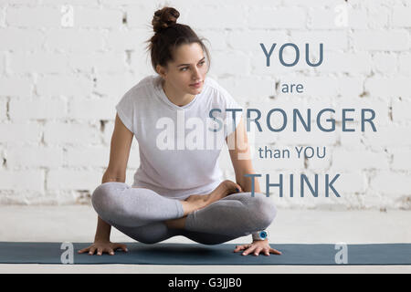 Belle jeune femme de l'exercice, faisant du yoga l'exercice sur tapis bleu. 'Expression de motivation Vous êtes plus fort que vous ne le pensez" Banque D'Images