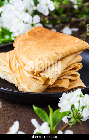 Crêpes maison pliée en triangles dans poêle à fond en fleurs au printemps Banque D'Images