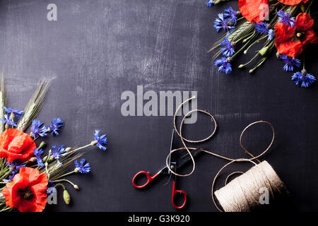 Coquelicots rouges et bleuet bleu avec le seigle sur les coins du vieux tableau noir avec des ciseaux, vue du dessus Banque D'Images