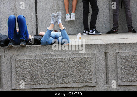 Plusieurs personnes se trouvant / Debout / Assis sur la base de la Colonne Nelson à Trafalgar Square à Londres, Angleterre Banque D'Images