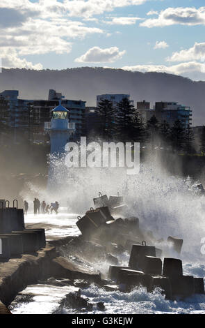 Les gens d'être éclaboussé par de grandes vagues de tempête sur le quai près de phare à Wollongong, New South Wales, Australie. Banque D'Images