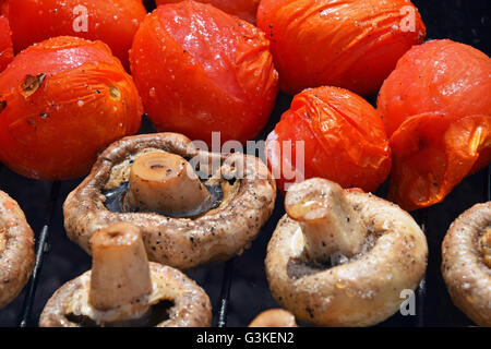 Dans les légumes de sel, d'épices et de la cuisson sur gril char, blanc champignons portobellos et petites tomates rouges Banque D'Images